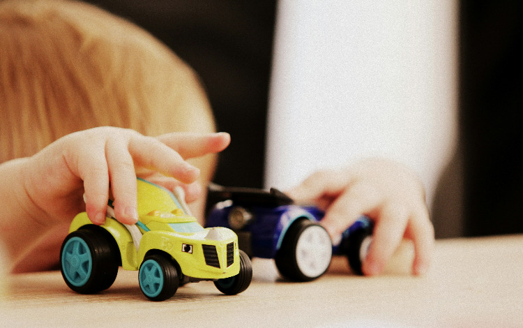 Kinderhände spielen mit Spielzeugautos auf einem Tisch in Österreich