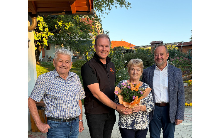 Josef und Maria mit Blumenstrauß im Garten, daneben ein Mann im schwarzen Weste und ein Mann im Sakko.