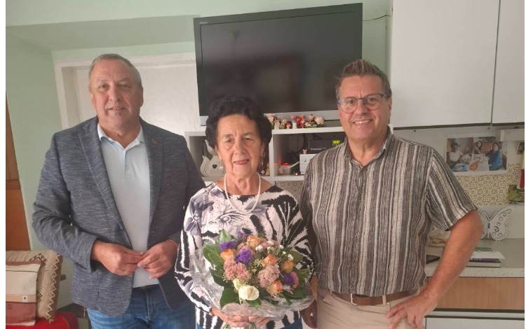 Drei Personen mit Blumenstrauß in Österreich, Frau mit Blumen, Mann mit Sakko, Mann mit gestreiftem Hemd.