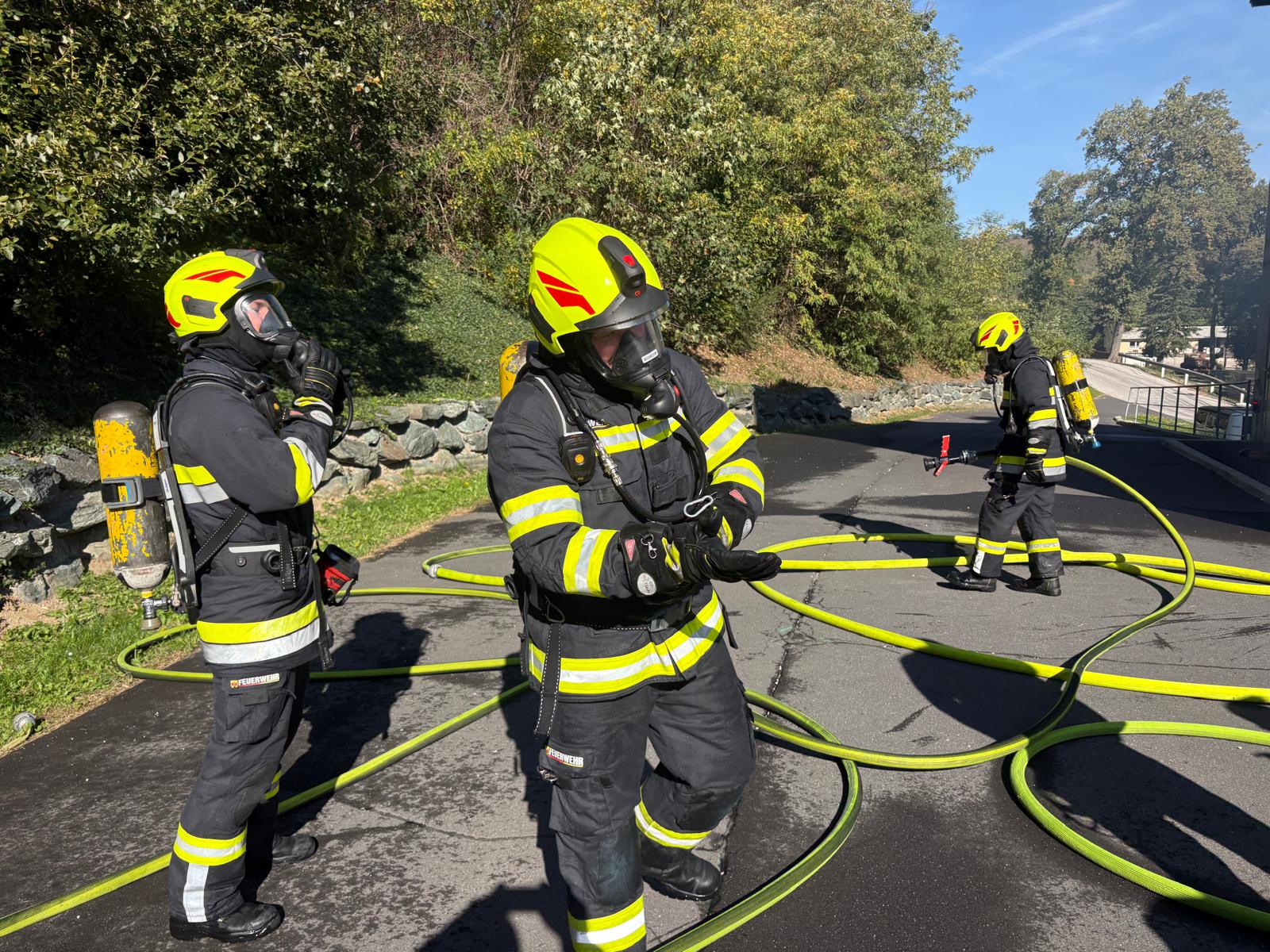 Feuerwehrleute mit Atemschutzgeräten und Schläuchen bei Übung in Österreich
