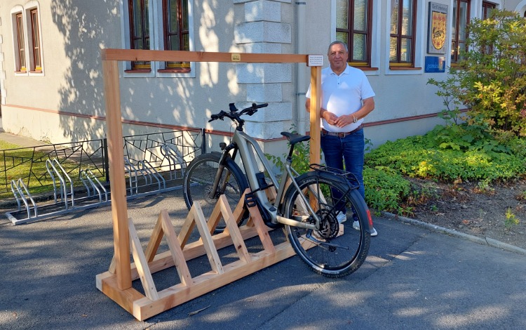 E-Bike auf Holzständer vor Gemeindeamt in St. Veit an der Glan, Mann steht daneben